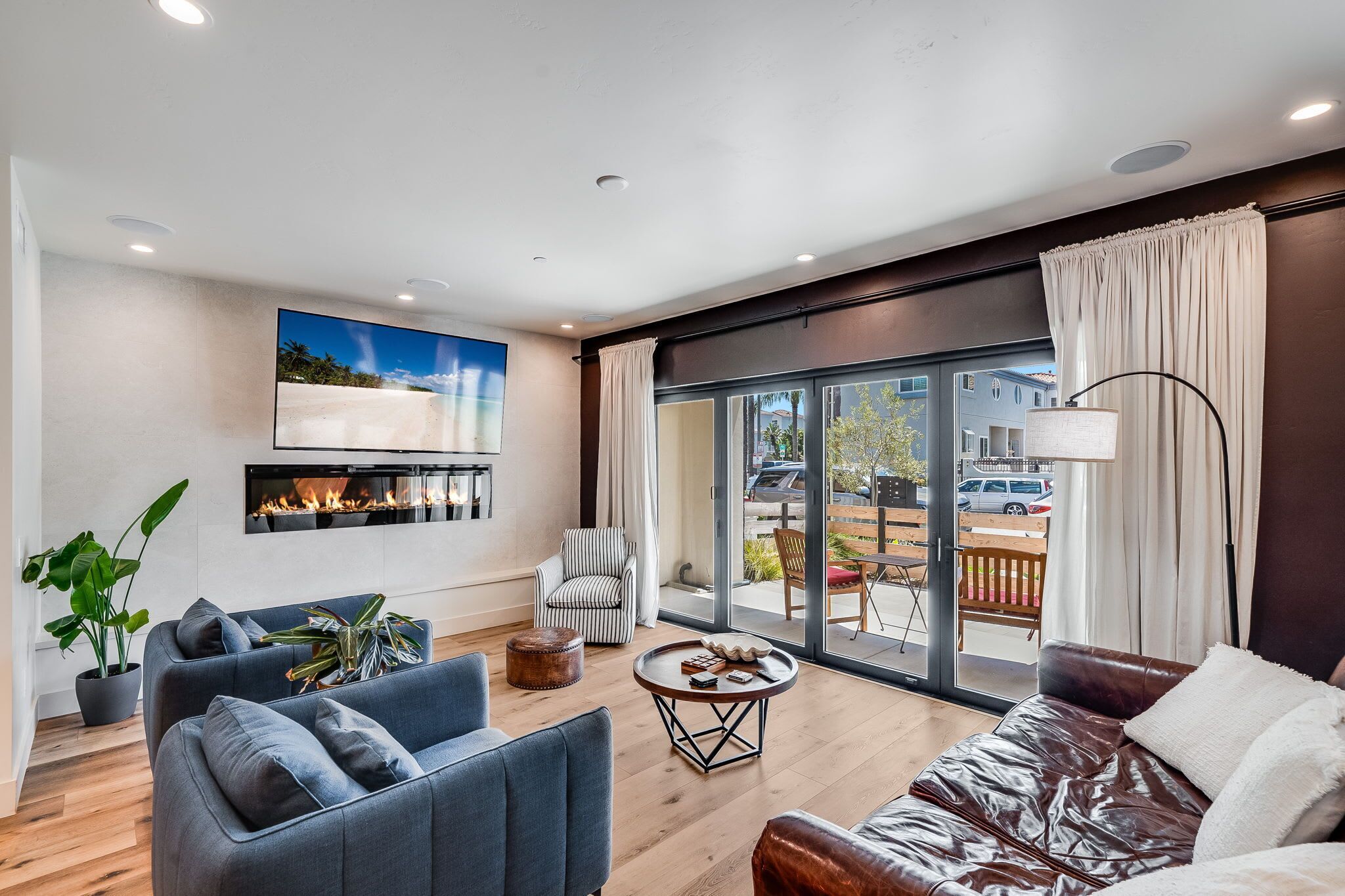 A modern living room with a fireplace, a large TV, and a view of the outside.