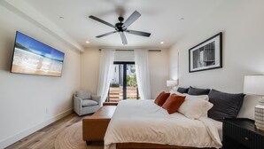 Una camera da letto con un letto, una ventola a soffitto, una televisione, una sedia, un comodino e vista sull'esterno.