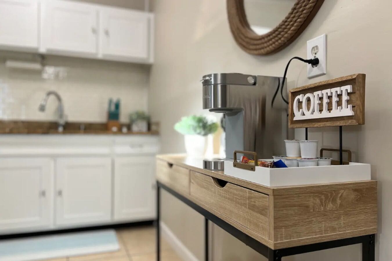 A kitchen with white cabinets, a coffee maker, and a coffee sign.