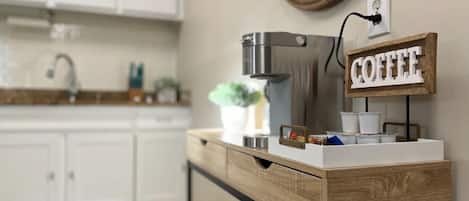 A kitchen with white cabinets, a coffee maker, and a coffee sign.
