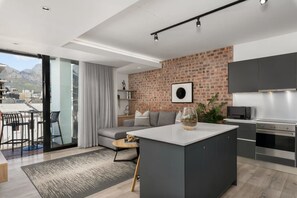 Eine moderne Küche mit Backsteinwand, ein Essbereich mit einer Couch und Blick auf die Stadt.