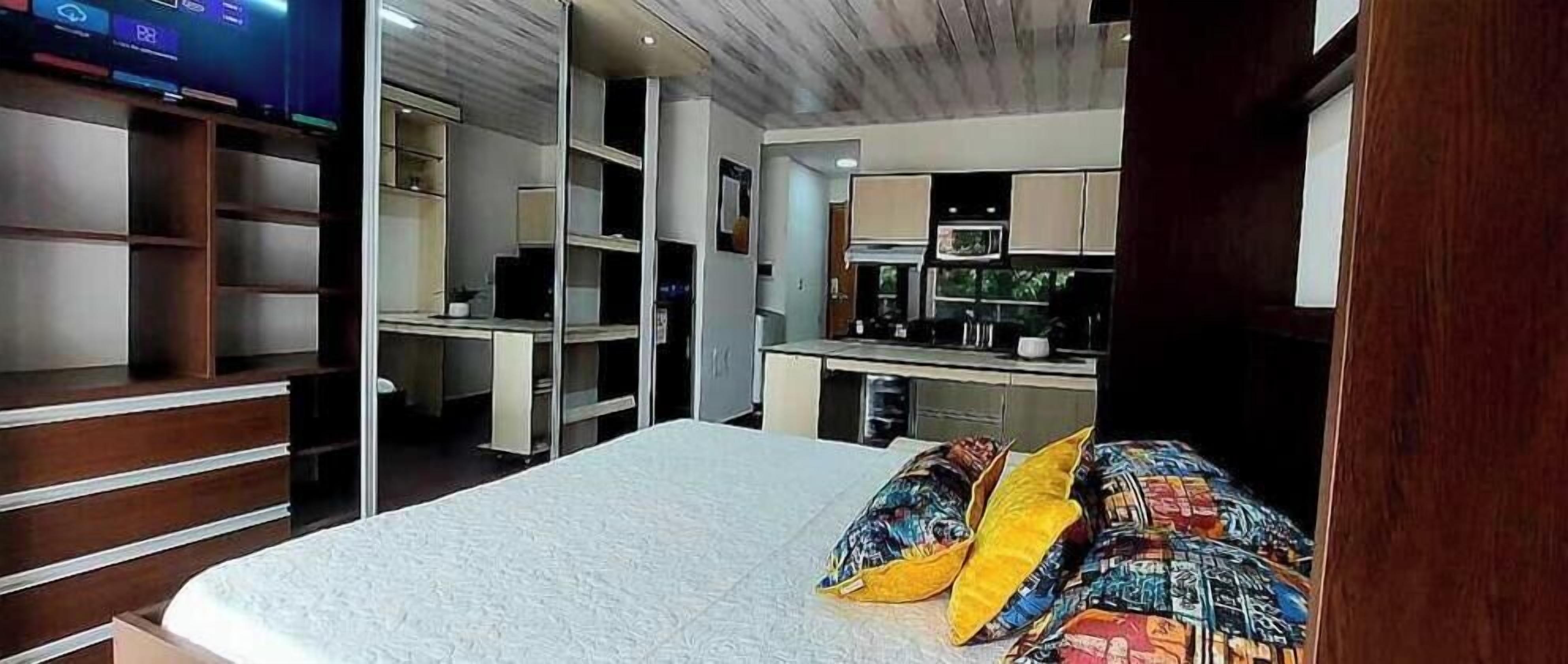 Une chambre avec un lit, une télévision, un bureau et un coin cuisine.