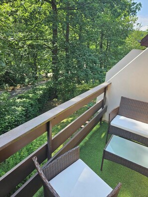 A balcony with wicker furniture and a view of a lush garden.
