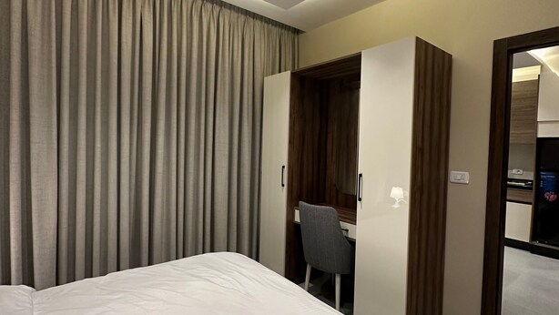 A hotel room with a bed, a desk, and a wardrobe. - 301 Al-najeh JRE Apartments For Rent ave (Amman)