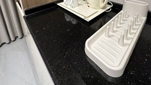 A modern kitchen with a black granite countertop, a coffee maker, and a kettle on a tray. - 301 Al-najeh JRE Apartments For Rent ave (Amman)