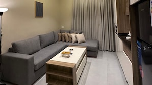 A modern living room with a grey sectional sofa, a wooden coffee table, and a flat-screen TV. - 301 Al-najeh JRE Apartments For Rent ave (Amman)