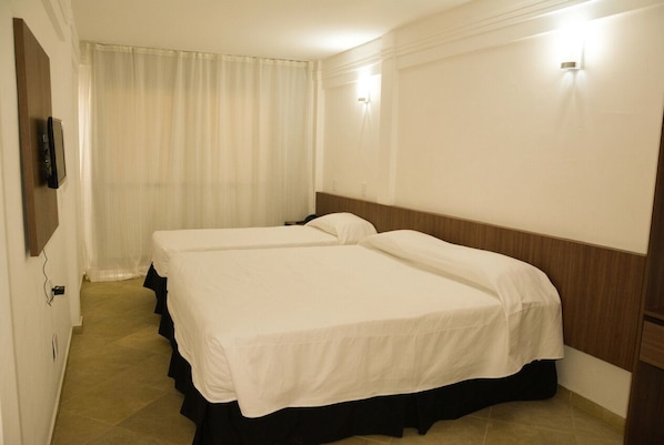 A hotel room with two beds, a television on the wall, and a curtain. - Hotel Waikiki Natal (Natal)