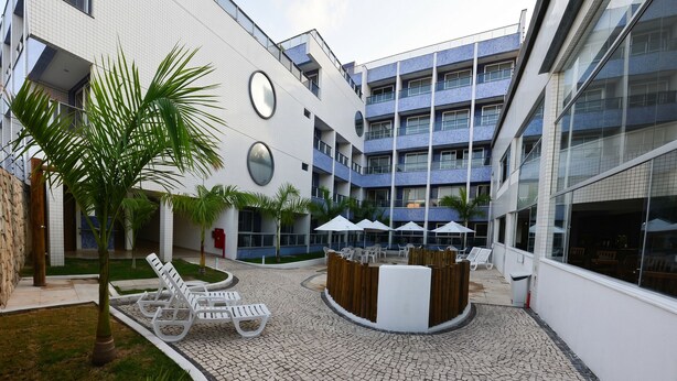 A courtyard with lounge chairs, palm trees, and a central seating area. - Hotel Waikiki Natal (Natal)