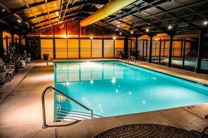 Ein Hallenbad mit klarem Wasser, umgeben von einem Metallzaun und einer überdachten Dachkonstruktion.