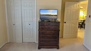 A room with a television on a wooden dresser, a closed white door, and a hallway leading to another room. - Welcome to Royale Retreat at Pointe Royal, in Branson, Missouri! (Branson)
