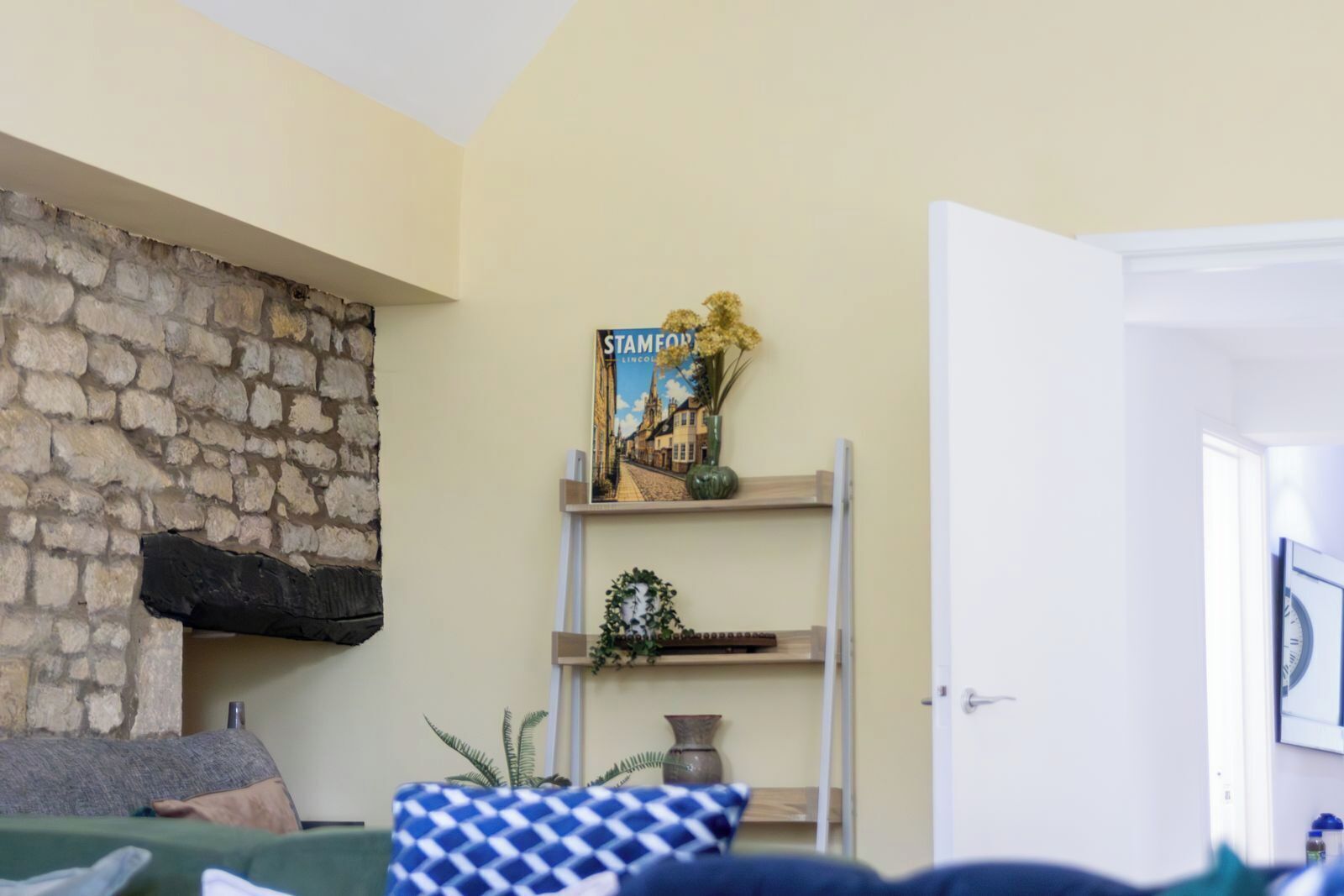 Una sala de estar con una pared de piedra, una estantería con un libro titulado 'Stamford Lincoln' y una puerta a la derecha.