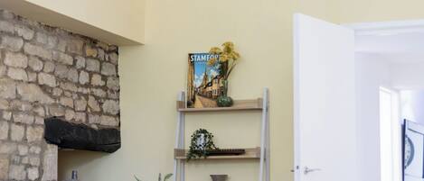 Una sala de estar con una pared de piedra, una estantería con un libro titulado 'Stamford Lincoln' y una puerta a la derecha.