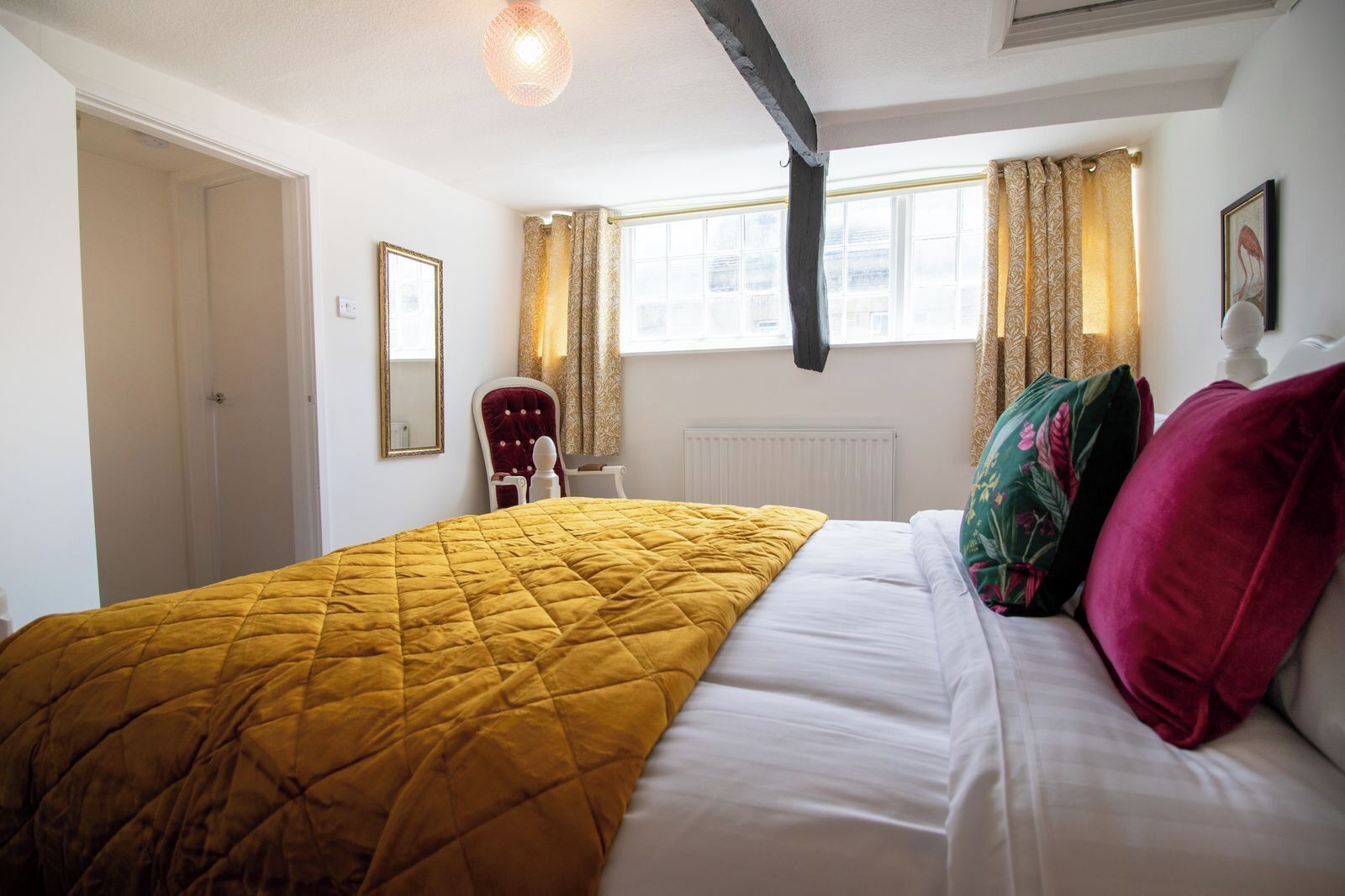 Een kamer met een bed, een stoel, een radiator en een raam met gordijnen.