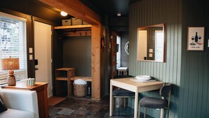 Una habitación acogedora con una mesa de madera, una silla, un sofá y una ventana con persianas.