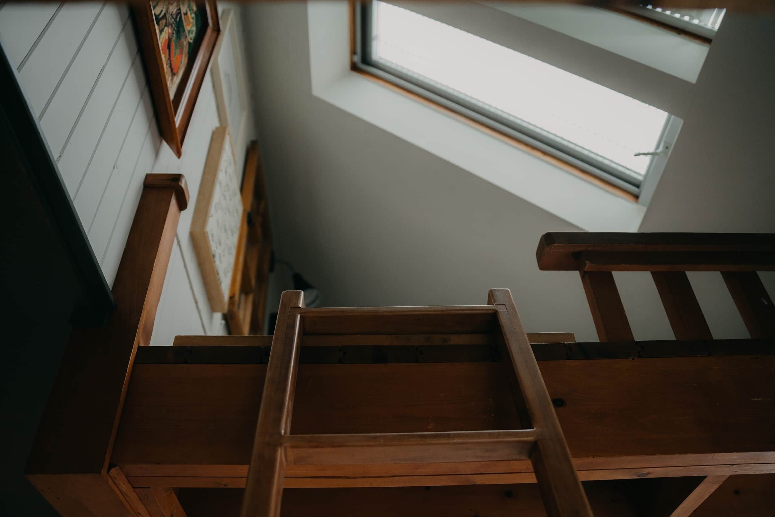 A wooden staircase leading to a room with a skylight.