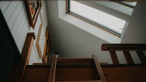 Una escalera de madera que conduce a una habitación con tragaluz.