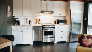 Una cocina moderna con gabinetes blancos, electrodomésticos de acero inoxidable y techo de madera.