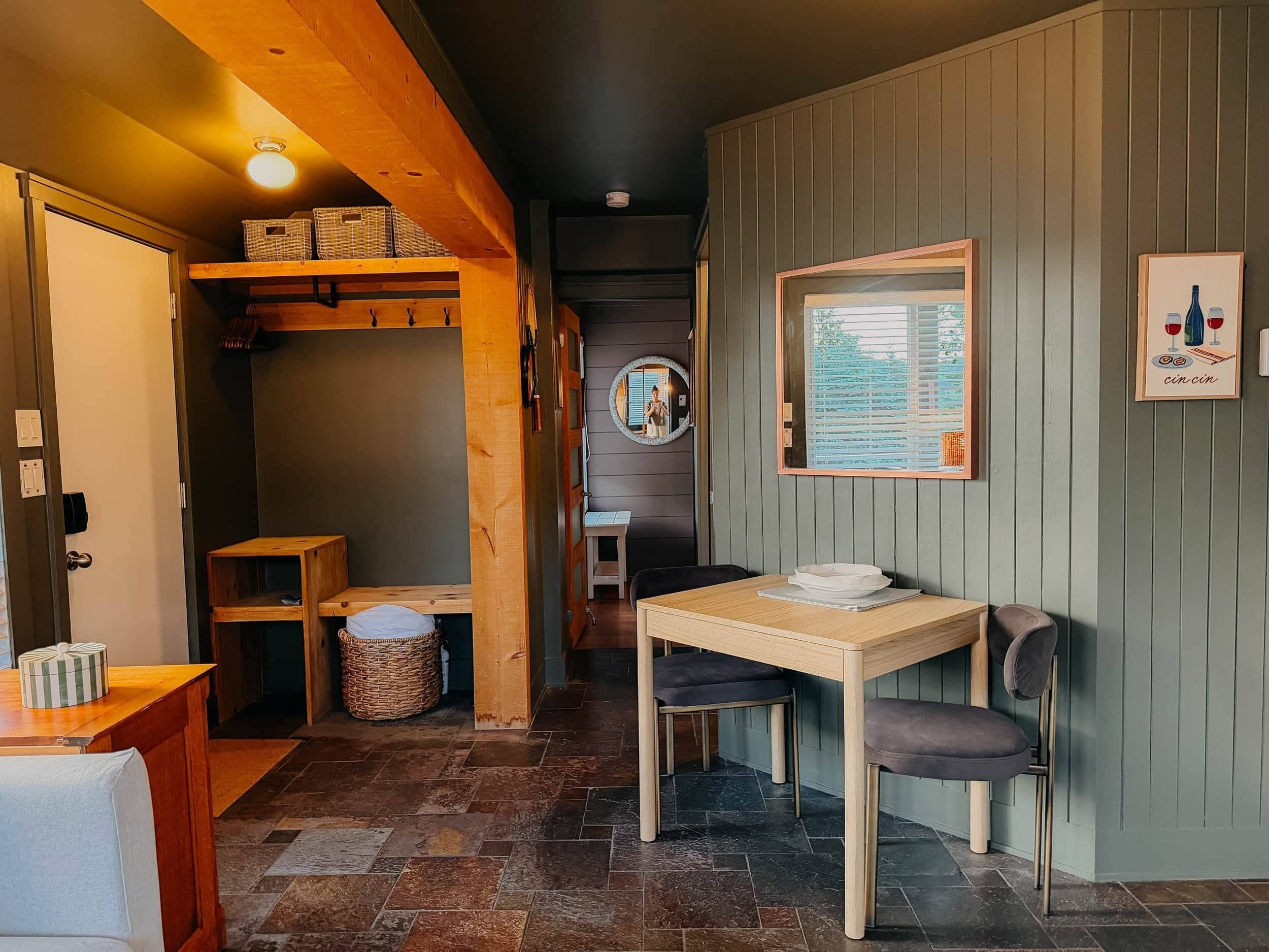 Una habitación acogedora con una mesa de madera, un banco y un espejo fijado a la pared.
