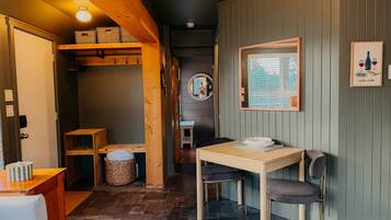 Una habitación acogedora con una mesa de madera, un banco y un espejo fijado a la pared.