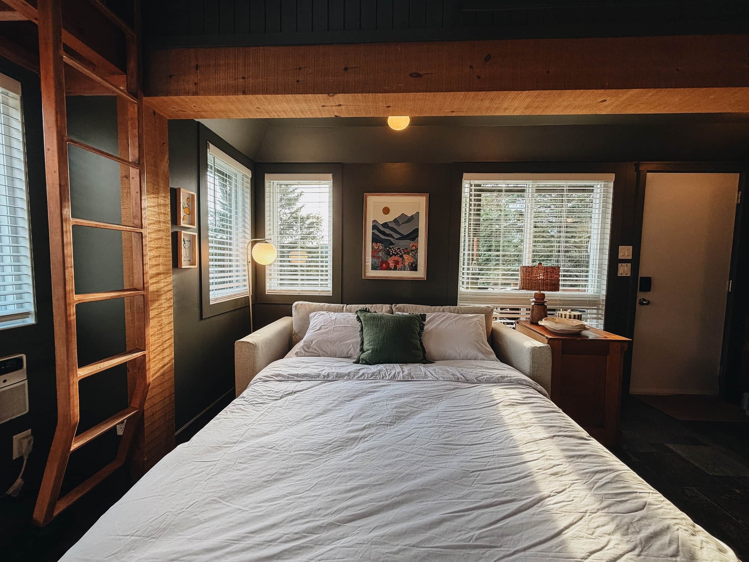 A bedroom with a bed, a nightstand, a lamp, and a window with blinds.