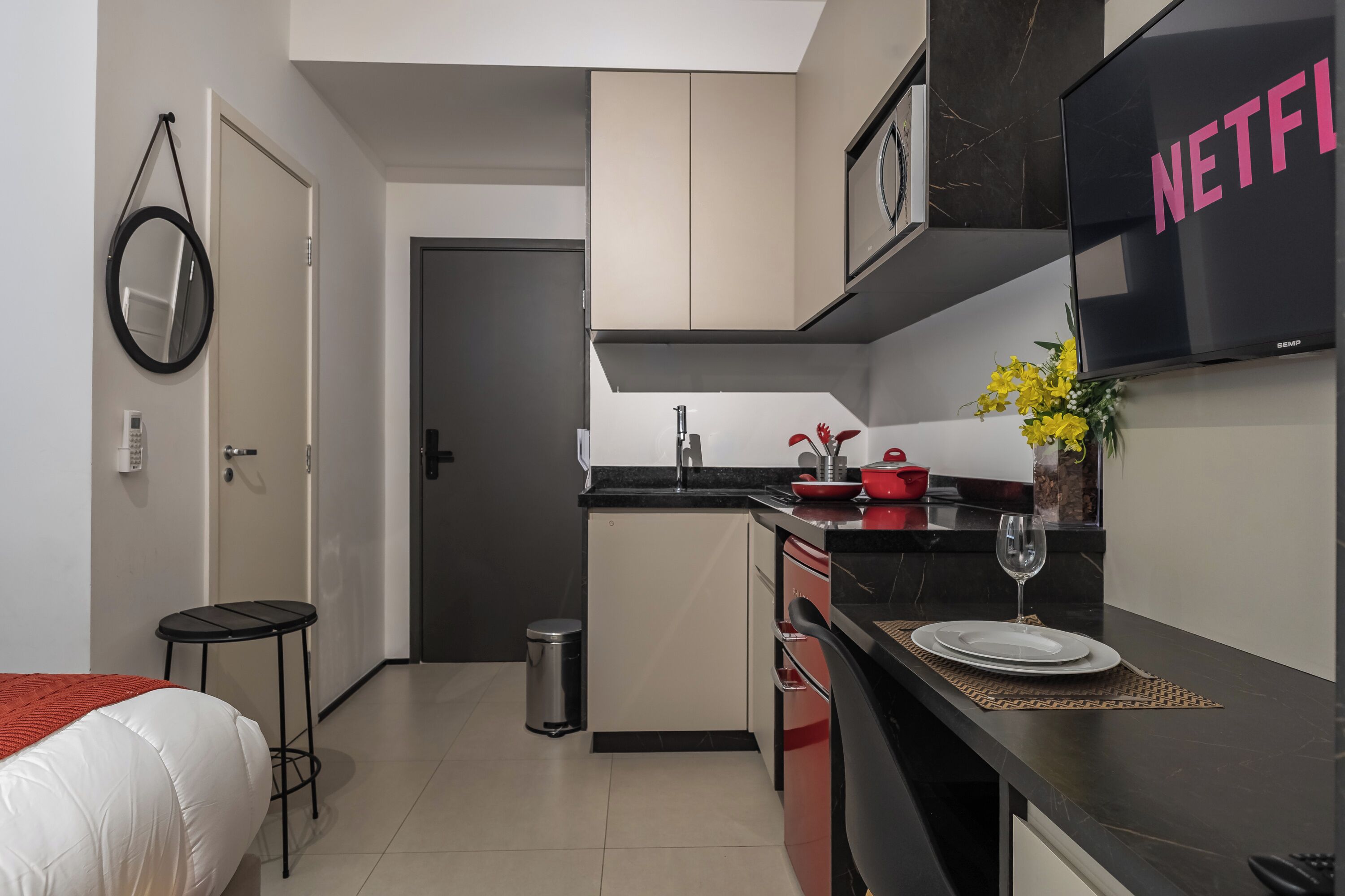 A modern kitchen with a black countertop, a sink, a small trash bin, and a dining area with a table set for two.