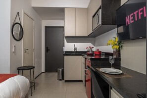 Eine moderne Küche mit schwarzem Arbeitsplatz, einer Spüle, einer kleinen Mülltonne und einer Essecke mit Tisch für zwei Personen.