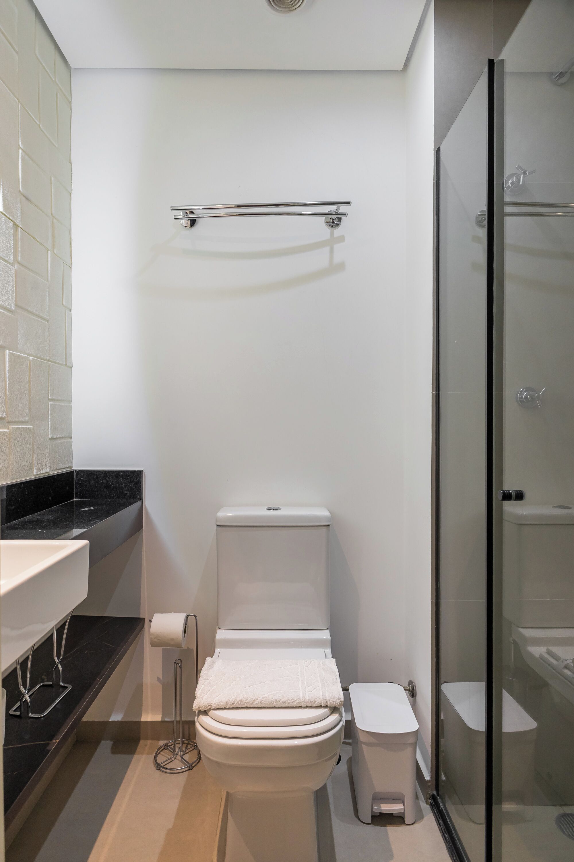 Een moderne badkamer met toilet, bidet en een douchecabine met glazen wanden.