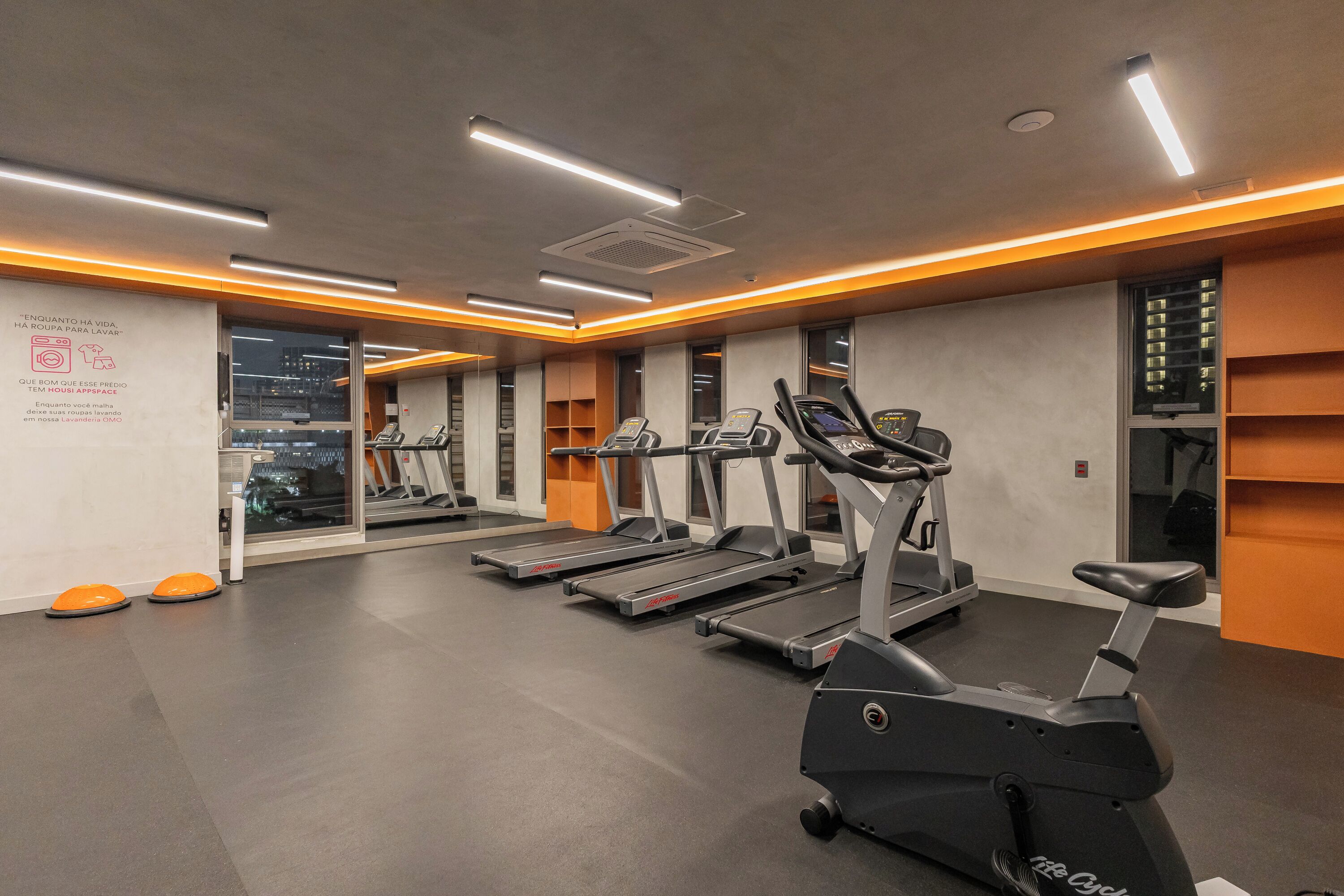 A gym with treadmills, ellipticals, and orange step platforms.