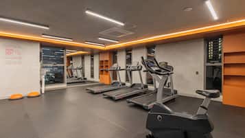 A gym with treadmills, ellipticals, and orange step platforms.