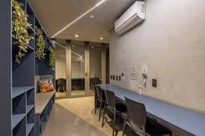 Une salle de conférence moderne, dotée d’une longue table, de chaises et d’un tableau blanc.