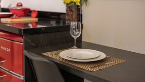 A dining table with a white plate, a wine glass, and a vase with yellow flowers. - StayHome VN Turiassu | Gym & Pool by Allianz Parque (São Paulo)