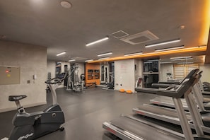 Une salle de sport équipée de vélos d’appartement, de tapis de course et d’appareils de musculation.