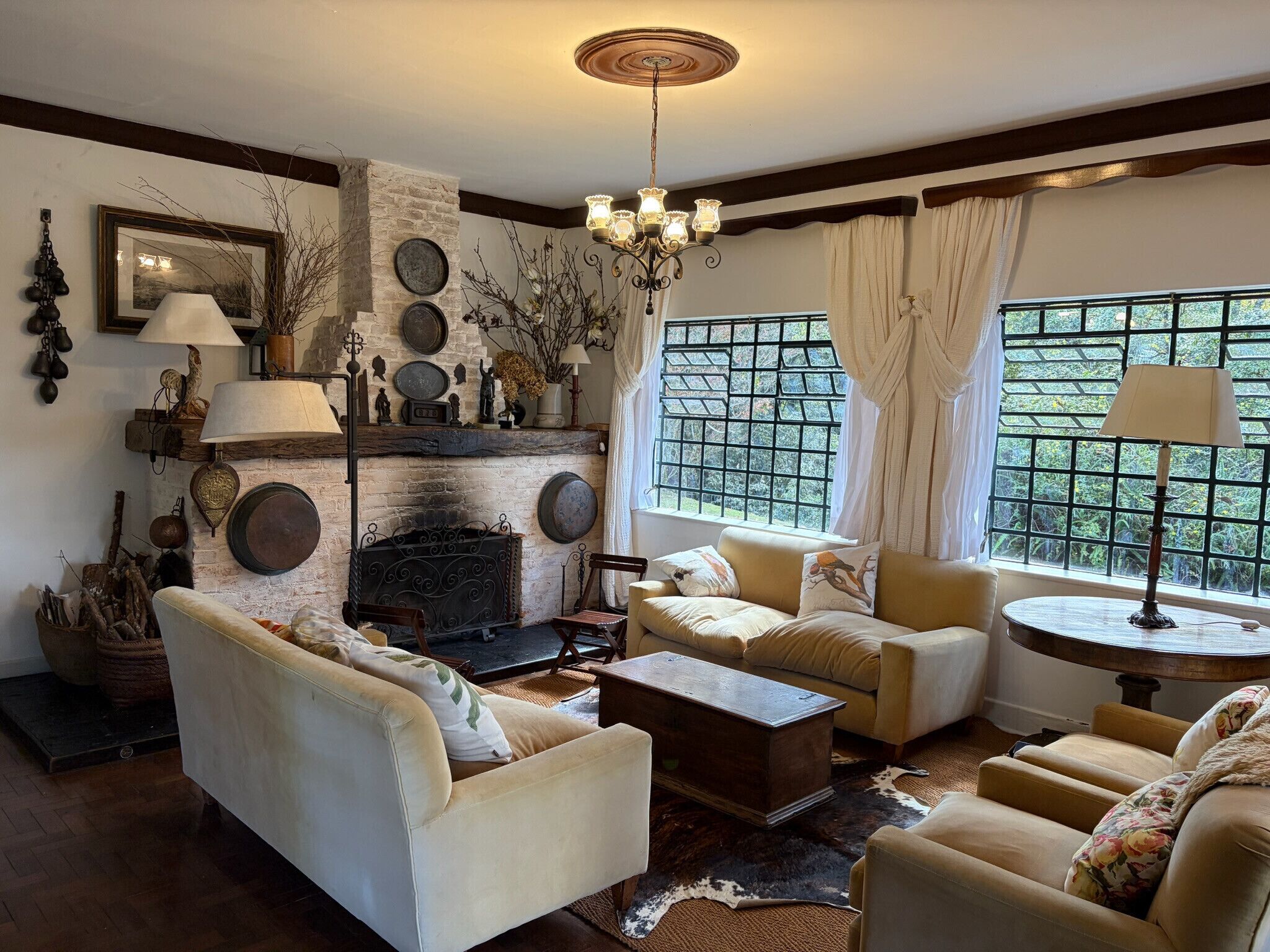 A cozy living room with a fireplace, comfortable seating, and a view through a window.