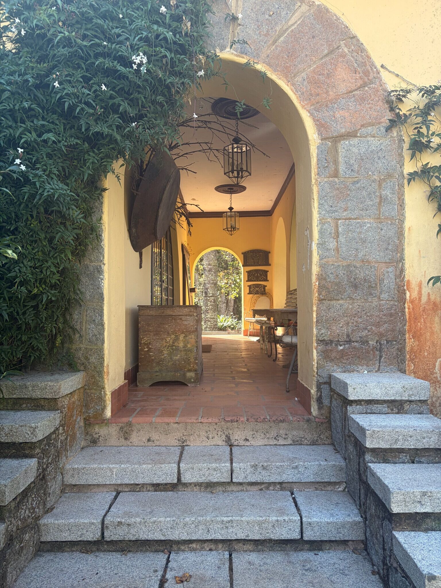 A stone staircase leading to an arched doorway with a lantern above, surrounded by greenery.