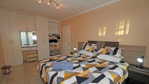 Un dormitorio con cama, mesitas de noche, armario y espejo.