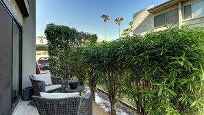 Eine Terrasse mit Korbmöbeln, einem kleinen Tisch und einem Blumentopf.
