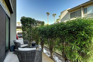 Eine Terrasse mit Korbmöbeln, einem kleinen Tisch und einem Blumentopf.