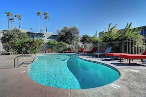A swimming pool with red lounge chairs, surrounded by palm trees and a fence. - Old Town Scottsdale, Covered Parking, Pool, Sleeps 6 (Scottsdale)