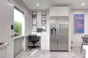 A modern kitchen with a built-in refrigerator, a water dispenser, and a dining area with a chair and table. - Old Town Scottsdale, Covered Parking, Pool, Sleeps 6 (Scottsdale)