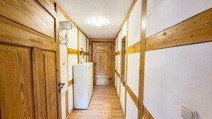 Un couloir aux murs en bois et un réfrigérateur blanc.