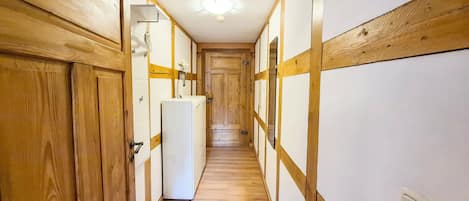 A hallway with wooden walls and a white refrigerator.