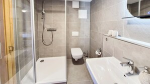 Une salle de bain moderne avec une douche à parois de verre, un lavabo blanc et des toilettes.