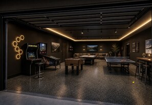 A modern indoor recreational area with pool tables, foosball, and arcade games.