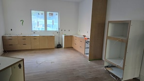 Een kamer met houten kasten, een raam en een gedeeltelijk gebouwd schap.