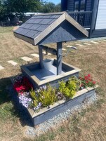 A garden feature with a metal structure, a wooden base, and a variety of flowers.