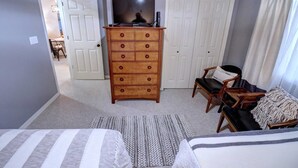 A bedroom with a dresser, a television on top, two beds, a chair, and a door leading to another room. - Welcome to Relaxation Pointe at Pointe Royale in Branson, Missouri! (Branson)