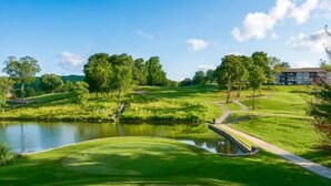 A golf course with a pond, trees, and a building in the background. - Welcome to Relaxation Pointe at Pointe Royale in Branson, Missouri! (Branson)