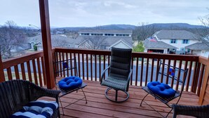 A wooden deck with two chairs and a table, overlooking a residential area with houses and hills. - Welcome to Relaxation Pointe at Pointe Royale in Branson, Missouri! (Branson)