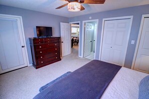 Ein Schlafzimmer mit Bett, Kommode und Deckenventilator.