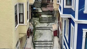 A narrow alleyway between buildings with a staircase leading to a second-floor entrance. - Redecorated Flat With Huge Library 100mbps (Istanbul)